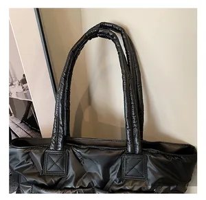 Detail of black quilted padded tote bag showing comfortable handle and shiny texture