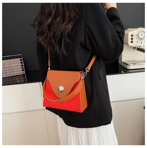 Detailed close-up of a color-block pleated box bag with red and brown leather contrast