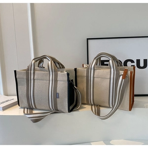 Detail of canvas tote bags with leather trim, striped handles and detachable shoulder straps