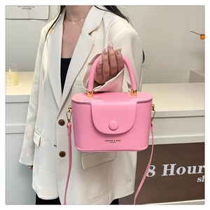 Detailed view of a pink structured box bag with gold lettering and adjustable strap