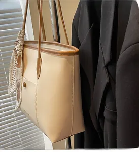 Close-up of off-white leather tote bag with brown trim and floral silk scarf detail