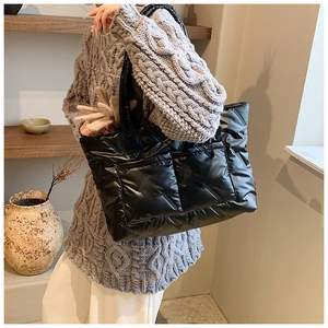 Detail of black quilted tote bag with padded texture and large front utility pockets