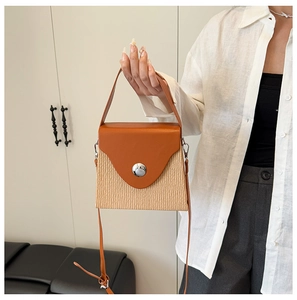 Close-up of a color-block crossbody bag featuring woven texture and a large silver buckle