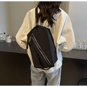 Detail of adjustable black nylon strap and reflective zipper on multifunctional sling bag