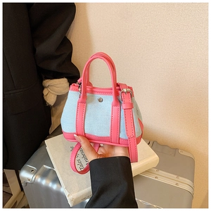 Detail of blue denim and pink leather mini crossbody bag with contrast stitching