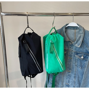 Detail of black and green nylon crossbody bags with diagonal zippers and reflective strips