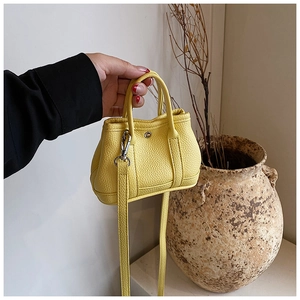 Detailed view of mini yellow leather handbag with lychee texture and silver hardware