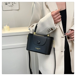 Close-up of black leather box bag with gold metal hardware and fashion text detail