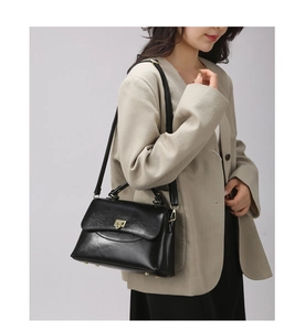 Detailansicht der eleganten schwarzen Lederhandtasche mit goldfarbenem Metall-Klappverschluss