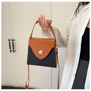 Detail of two-tone crossbody box bag with caramel top handle and silver buckle