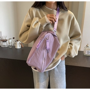 Close-up of purple nylon crossbody bag with dual zippers and wide shoulder strap detail