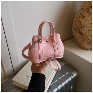 Close-up of pink mini crossbody bag in lychee pattern leather with silver hardware