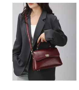 Detailansicht der weinroten Ledertasche mit elegantem Golddrehverschluss und Griff