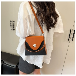 Model wearing a color-block shoulder bag with orange flap and black pleated texture