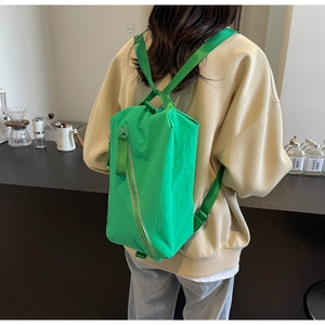 Rear view of a bright green nylon backpack shown in a modern cafe setting