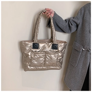 Detail of metallic gold quilted tote bag featuring double front pockets and reinforced handles