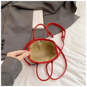 Detail of red mini crossbody bag with lychee grain texture and magnetic buckle
