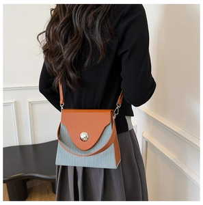 Detail of color-block crossbody bag with orange leather flap and pleated grey texture