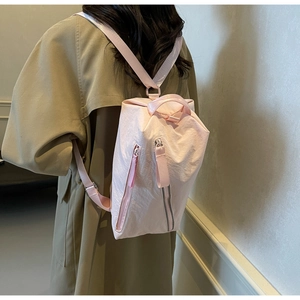 Rear view of a minimalist pink nylon backpack worn with a casual khaki trench coat