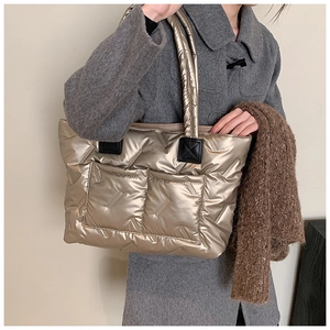 Detail of metallic gold quilted tote bag showing waterproof fabric and outer pockets