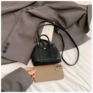Micro black lychee leather handbag shown next to a smartphone to illustrate mini size