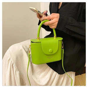 Detail view of the bright green box bag with golden hardware and leather texture