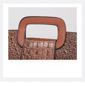 Detailed close-up of brown crocodile embossed leather and sturdy handle stitching on tote bag