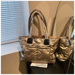 Detail of gold metallic quilted tote bag with herringbone stitching and front pockets