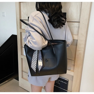 Detail of black leather tote bag with flap pocket and decorative geometric silk scarf