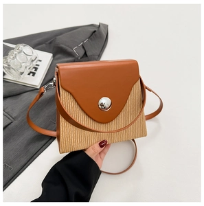 Detail of a brown leather box bag with vertical stripes and a large silver metal buckle