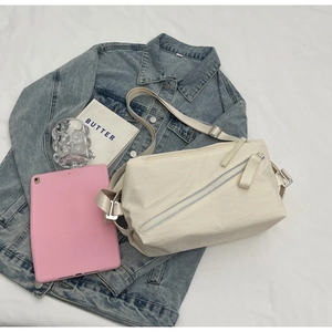 Detail of off-white nylon shoulder bag with diagonal zipper pocket on textured fabric