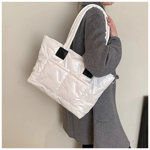 Close-up of white quilted puffer tote bag with glossy waterproof fabric and front pockets
