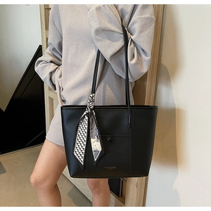 Detail of black leather tote bag with decorative silk scarf and front snap pocket