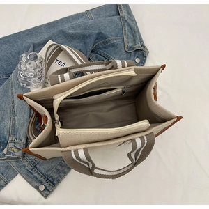 Detailed interior of a canvas tote bag showing the zipper compartment and striped strap