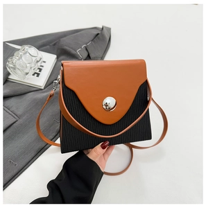 Detail of trendy color-block box bag featuring pleated black body and brown flap cover