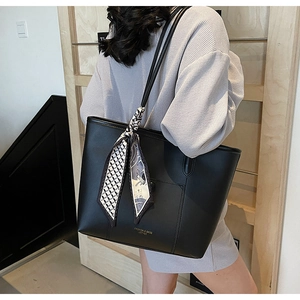 Detail of black leather tote bag with elegant silk scarf and gold brand lettering