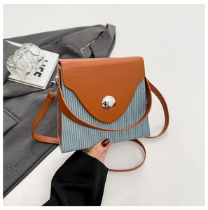 Detail view of stylish color-block crossbody bag with orange leather flap and blue striped body