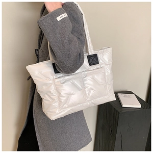 Detail of white quilted tote bag featuring padded nylon texture and black leather accents