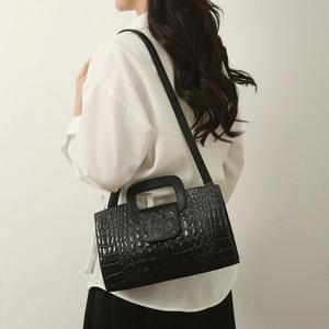 Detail of black crocodile pattern leather tote bag with sturdy handles and shoulder strap