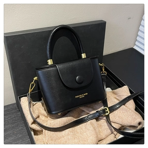 Close-up of black leather box bag in gift box with golden logo and fine strap