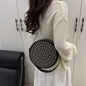 Black round rivet shoulder bag with silver metal chain strap shown on a female model
