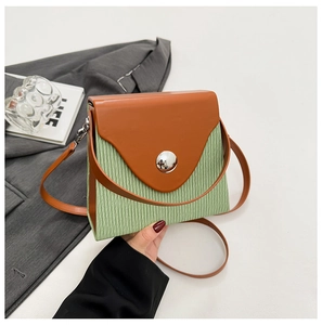 Detailed macro view of green pleated texture and brown leather flap on a box bag