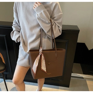 Detail of dark brown tote bag with geometric silk scarf shown on model for daily commute
