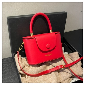 Detail view of red leather box bag with round handle and adjustable shoulder strap