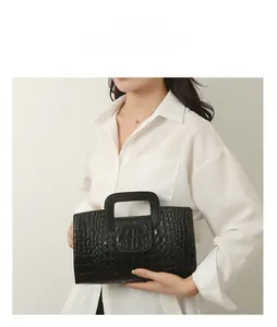 Detail of black crocodile pattern tote bag with unique square handle shown by model