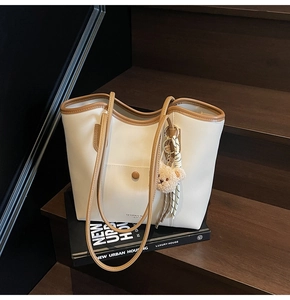 Top-down view of a beige tote bag with brown straps on a book and wooden stairs