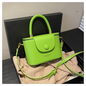 Lime green minimalist leather box bag with round handle inside a black gift box