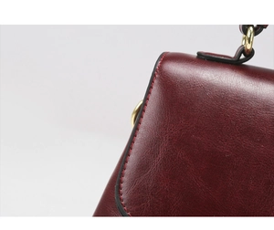 Macro shot of burgundy leather edge with neat stitching and gold hardware detail