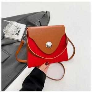 Detail of color-block crossbody bag with red pleated texture and large silver buckle