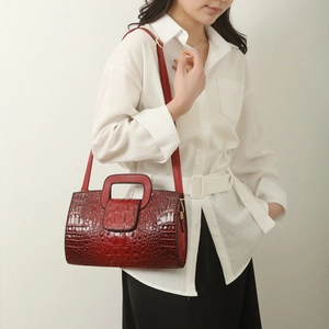 Detail of red croc-embossed tote bag featuring gold hardware and a detachable strap